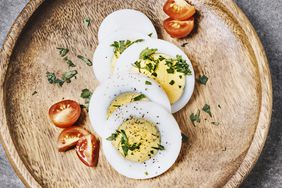 air fryer hard-boiled eggs with herbs and tomato on a wooden plate