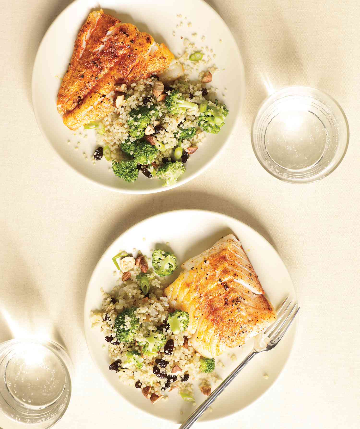 Overhead View of Two White Plates of Spiced Cod With Broccoli-Quinoa Pilaf, an easy and fast dinner recipe.