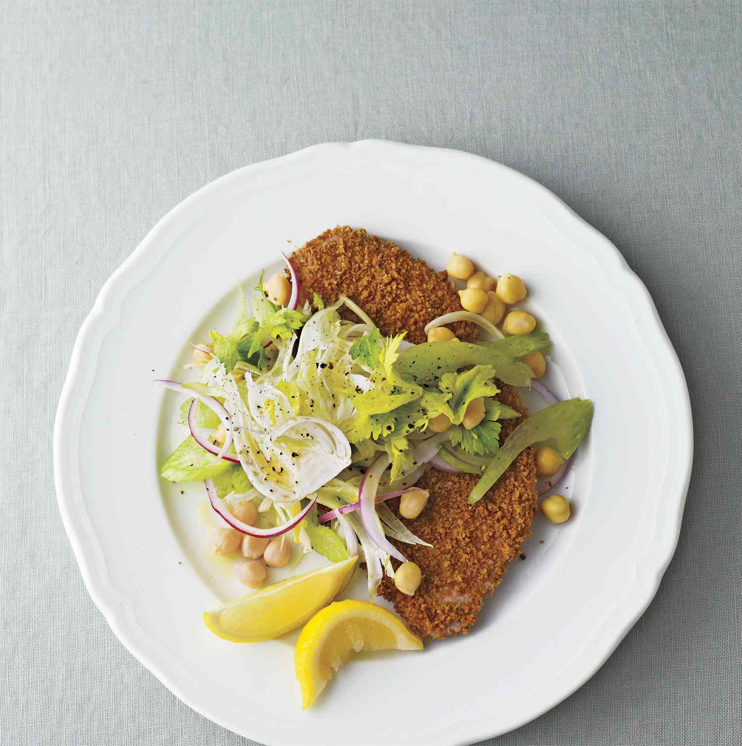 Crispy Pork Cutlets With Fennel-Chickpea Slaw, Served With Lemon Wedges on a White Plate