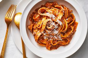 Walnut Mushroom Bolognese Pasta in a White Bowl with Bronze Fork and Spoon to its Left