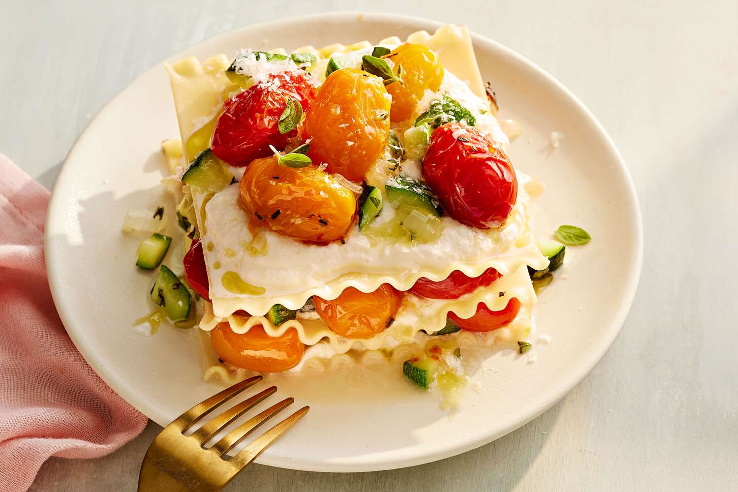 No-Bake Summer Veggie Lasagna Topped With Cherry Tomatoes, Served on a White Plate With a Metal Fork for Eating