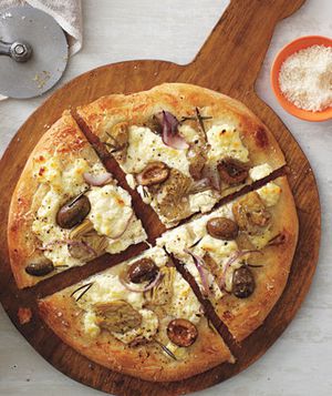 White Pizza With Artichokes, Rosemary, and Olives Served on a Wooden Pizza Board