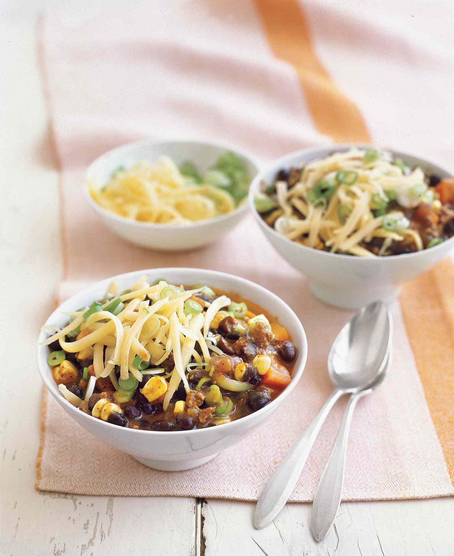 Two White Bowls Full Southwestern Beef Chili With Corn, a quick dinner recipe, Topped With Shredded Cheese
