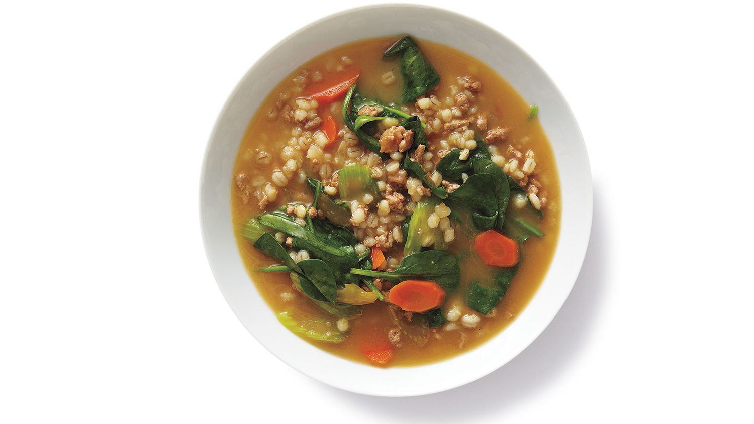 Overhead view of turkey-barley vegetable soup served in a white bowl