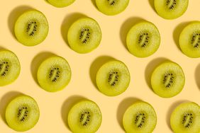 Slices of green kiwi fruit on a pale yellow background